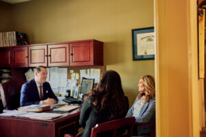 Attorney Dan Stampone leads a chat in his office with two team members